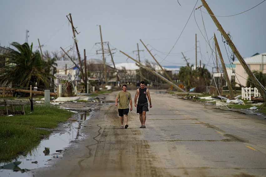 Two men walking down destroyed street in Homa, LA after Hurricane Ida
